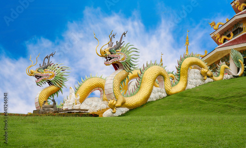 Golden yellow Chinese dragon at Huai Pla Kung Temple, a bublic Chinese temple in Chiang Rai Province, Thailand, against a blue sky background. photo