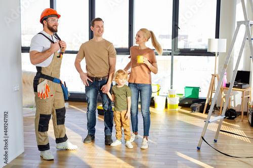 Young caucasian family with child admire the renovations in new home talking with pleasant constructor, having nice conversation, discussing details, side view portrait