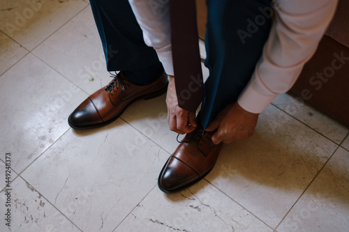 Groom is tying the laces on his shoes. Close-up