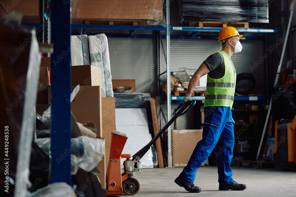 Warehouse worker with face mask pulls packages on pallet jack at storage compartment. Warehouse worker with face mask pulls packages on pallet jack at storage compartment.