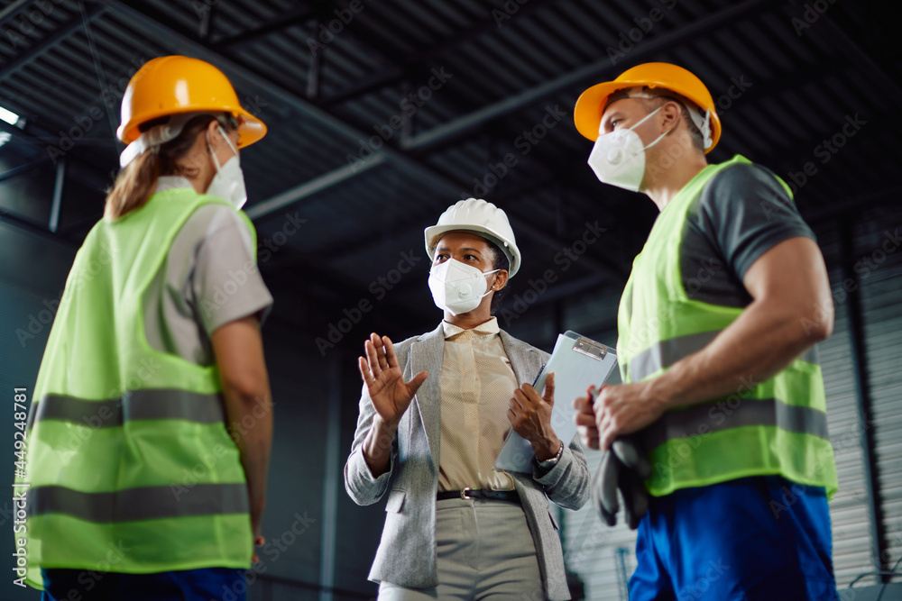 Below view of African American supervisor communicates with warehouse workers during COVID-19 pandemic.