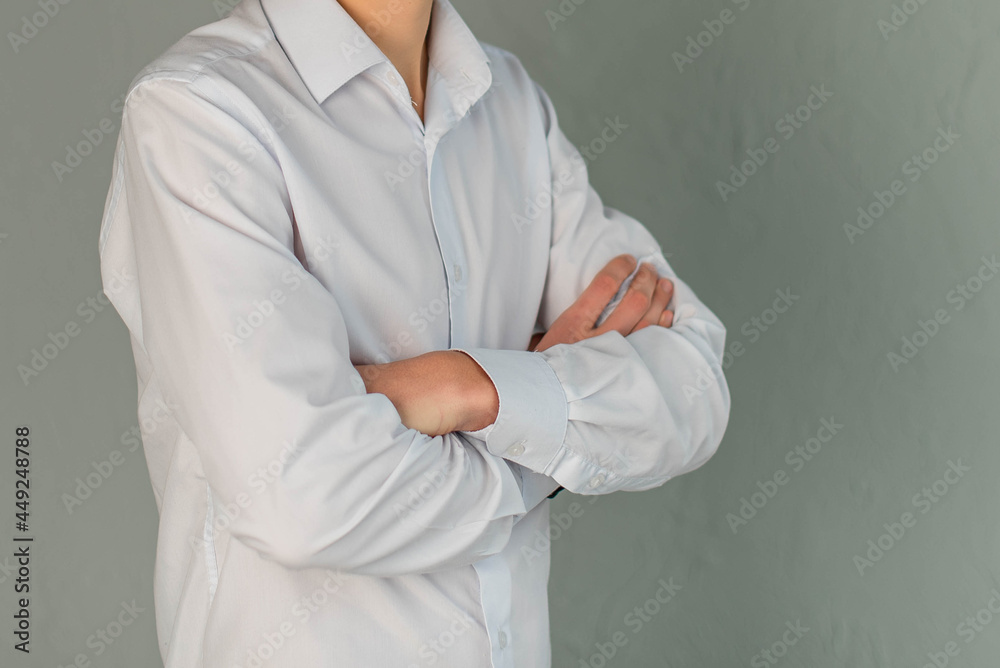 A young man in a white shirt and stands on a gray background. A young man in a white shirt and stands on a gray background.