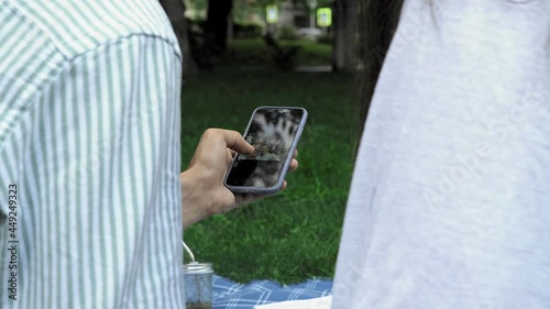 A man's hand holds a phone and flips through photos in nature in the summer