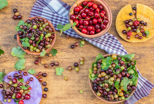 Summer harvest of berries, gooseberries, cherries, currants on a wooden background, top view 