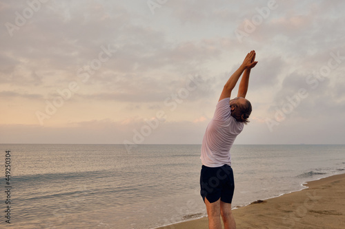 Man doing Surya Namaskar or Salute to the Sun or Sun Salutation. Man practices yoga at sea beach during sunrise