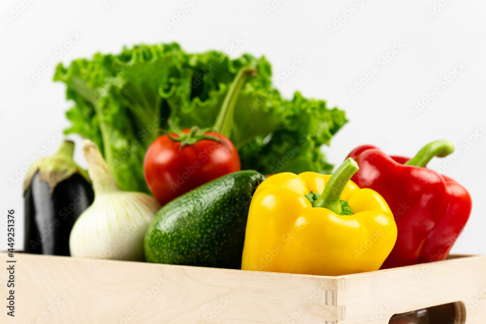 Fresh vegetables in a wooden box. Lettuce, peppers, tomatoes, avocado, eggplant, onions in close-up. Delivery and healthy food concept