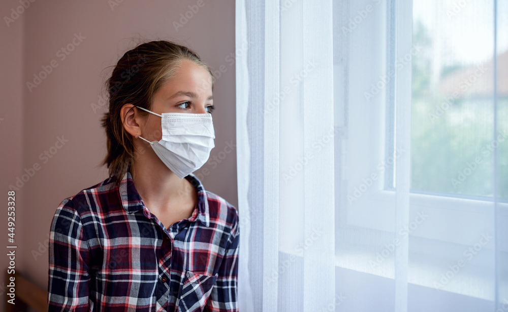 Quarantine. Worried little girl with medical mask on her face looking from room through the window. Medical concept Quarantine. Worried little girl with medical mask on her face looking from room through the window. Medical concept