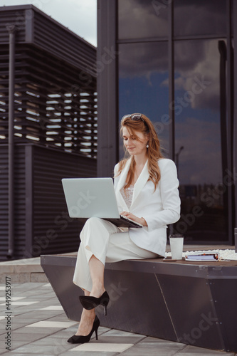 Portrait of cute young business woman outdoorwith coffee and laptop photo