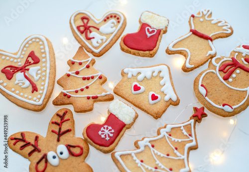 Top view of homemade Christmas gingerbread cookies decorated with red and white colored royal icing and different shapes on white background. Festive dessert and holidays celebration concept.