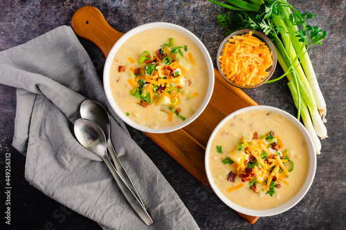 Bowls of Loaded Baked Poatos Soup Topped with Sour Cream, Cheddar Cheese, Bacon, and Chives: Creamy potato soup garnished with sour cream, shredded cheese, bacon bbits and chives photo