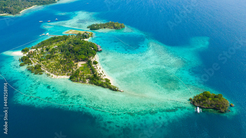 Top view of small tropical island in the blue sea with a coral reef and the beach. Malipano island, Philippines, Samal.