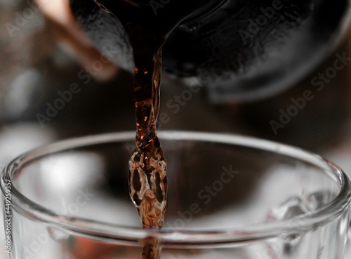 stream of pomegranate juice pours into a transparent glass photo