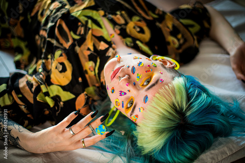 Closeup fashion portrait young pretty beautiful girl with green and blue hair. Beautiful fashion girl with luxury professional makeup and funny emoji stickers glued on the face. Young woman