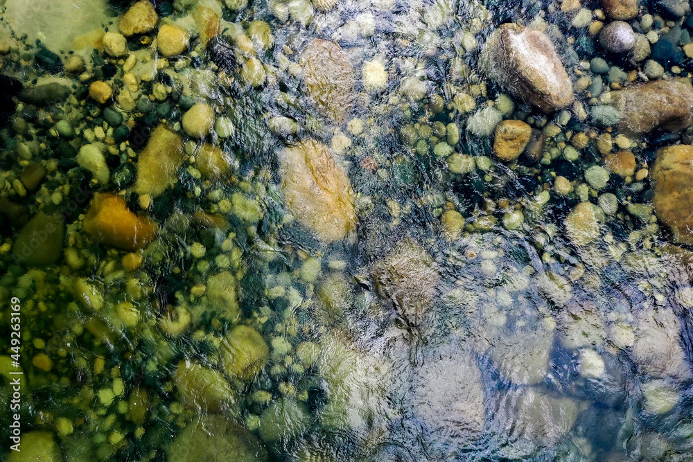 Relaxing view of pebbles, stones and rocks visible through the watersurface, seen from above