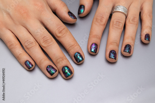 Women s well-groomed hands with black glitter manicure. Gel polish coating