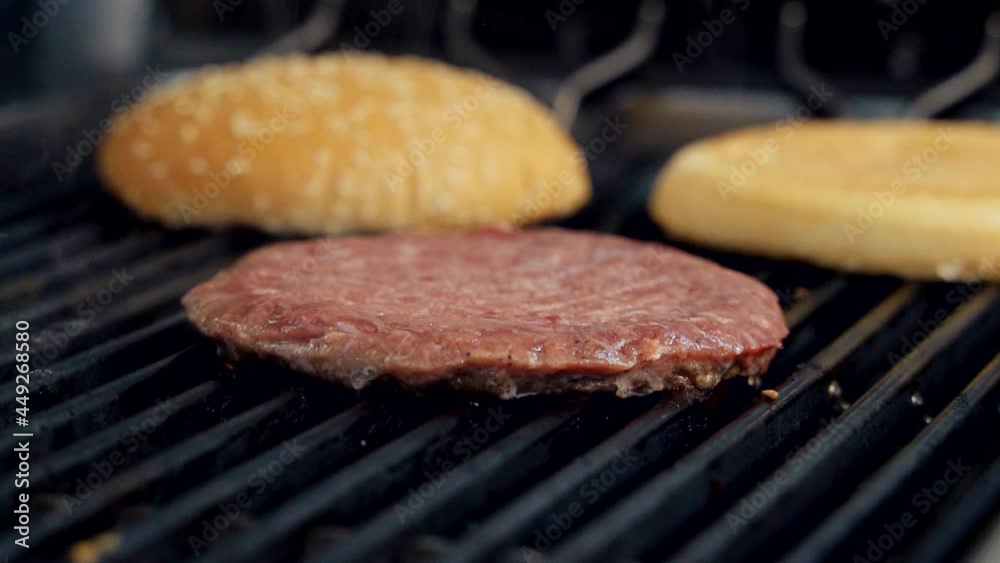 Cooking meat cutlet and buns on hot grill. Process of frying tasty components for burger. Beef cutlet frying in fast food restaurant. Close-up. Cooking meat cutlet and buns on hot grill. Process of frying tasty components for burger. Beef cutlet frying in fast food restaurant. Close-up.