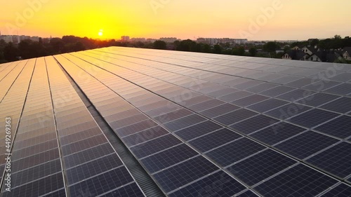 Blue photovoltaic solar panels mounted on building roof for producing clean ecological electricity at sunset. Production of renewable energy concept.