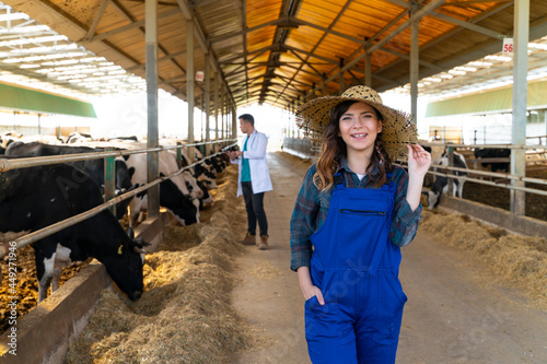 Portrait of female farm worker touching her hat in cowshed © bulentbaris