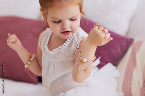 Cuadro en lienzo cute baby girl trying on a lot of finger rings and bracelets, bijou jewelry