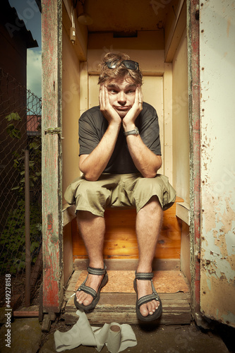 Man using wooden toilet latrine on summer cottage photo