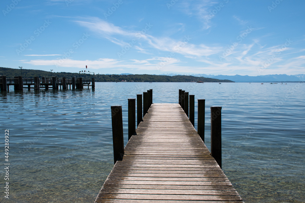 Wooden jetty projecting into Lake Starnberg in Starnberg in Bavaria, Germany, on a sunny summer day