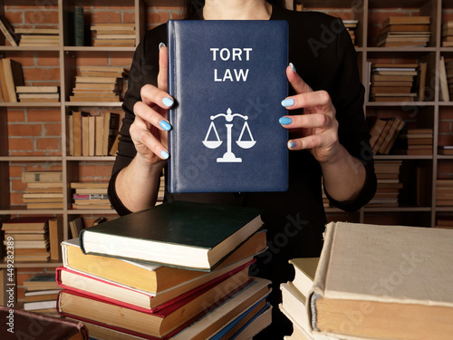 Lawyer holds TORT LAW book. A tort occurs when someone commits a wrong against another person photo