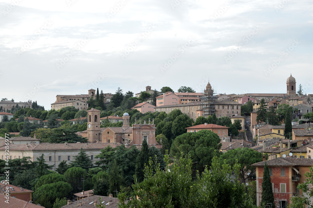scenery view of old houses in a town with a trees and part o  in the back , italy , perugia city .