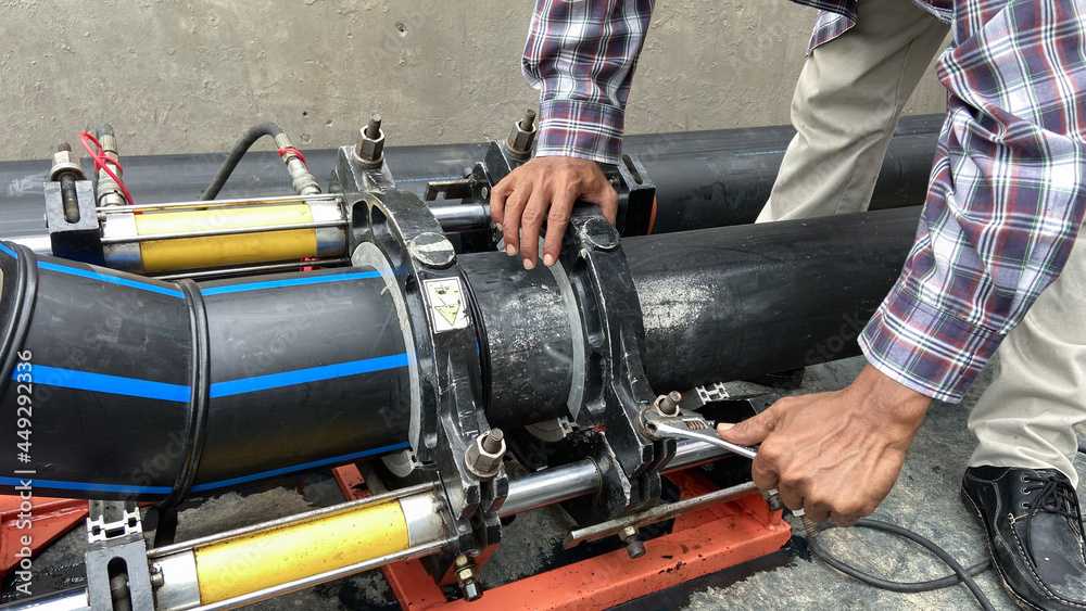 Plumber installs a hydraulic PE pipe welding machine for connecting water pipes in the factory. Plumber installs a hydraulic PE pipe welding machine for connecting water pipes in the factory.