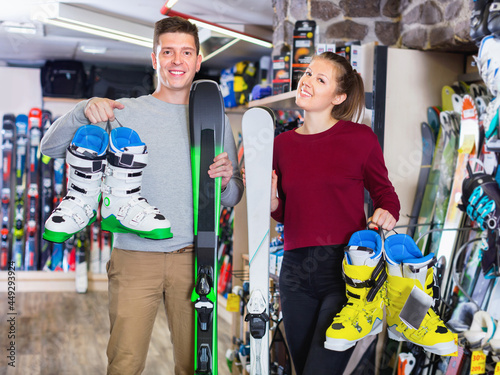 Happy cheerful positive smiling woman and man are demonstrating their choice of ski boots