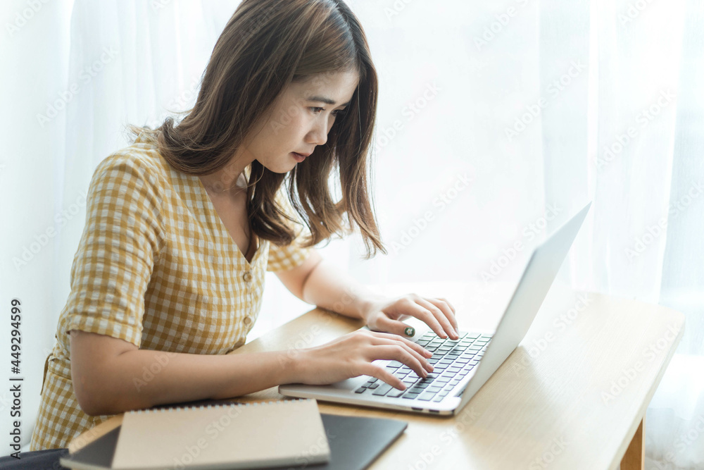 Entrepreneur concept a young female freelancer working on her laptop device typing an urgent document seriously Entrepreneur concept a young female freelancer working on her laptop device typing an urgent document seriously