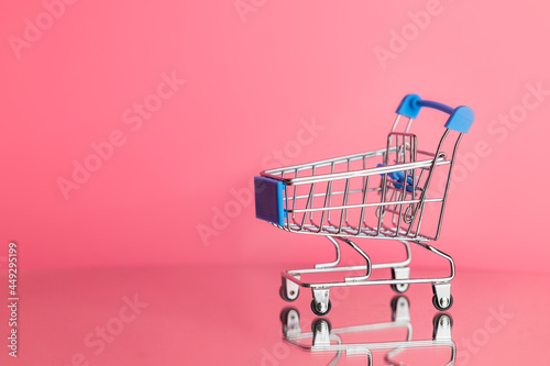 shopping cart on fresh pink background with copy space.
