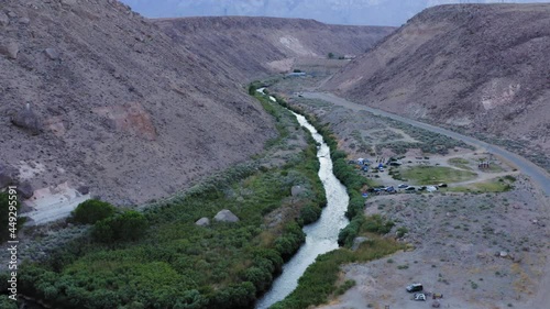 Top view of the river and its parallel road.Aerial dron shot view: flying near mountain range valley. Mountain river flowing between high roky mountains photo