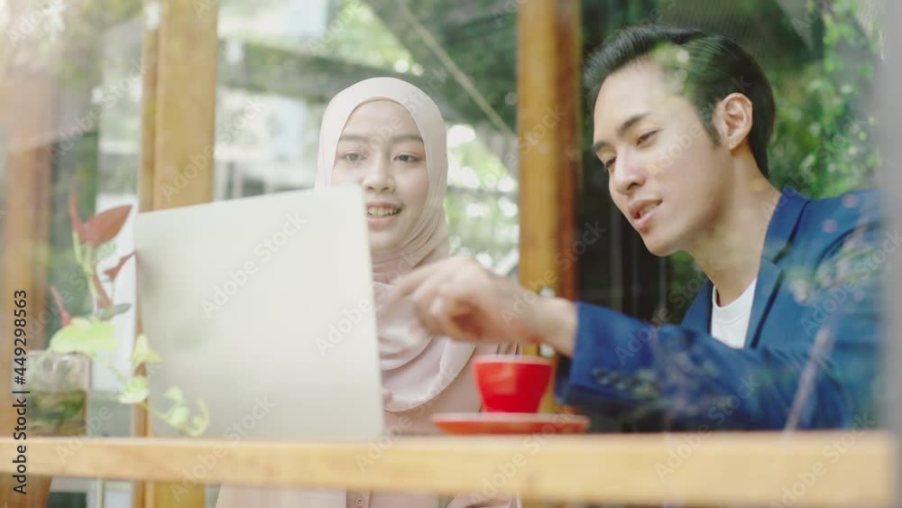 Upwardly mobile Asian Muslim business man - women entrepreneur sitting by the window on a bright sunny day discussing sale and marketing analysis, Asian Muslim SME teamwork e-commerce concept Upwardly mobile Asian Muslim business man - women entrepreneur sitting by the window on a bright sunny day discussing sale and marketing analysis, Asian Muslim SME teamwork e-commerce concept