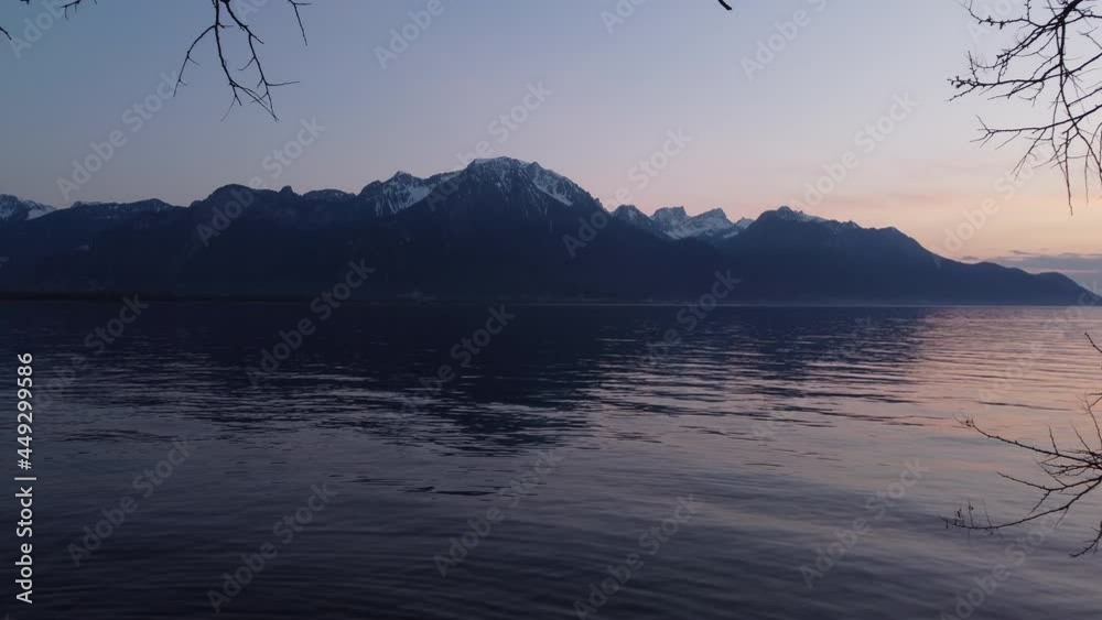 Slow aerial fly through shot low above Lake Geneva with Alps in frame during a vibrant sunset. Slow aerial fly through shot low above Lake Geneva with Alps in frame during a vibrant sunset.