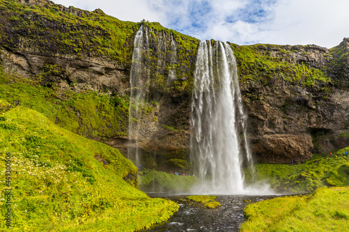 Typical landscape for the summer in Iceland. At the foot of the waterfall Seljalandsfoss crowds of tourists