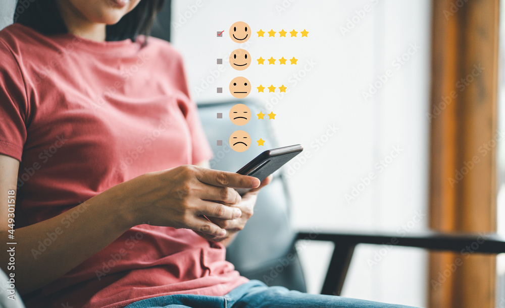 Woman using smartphone pressing the happy face to Customer experience services rating concept. - obrazy, fototapety, plakaty 