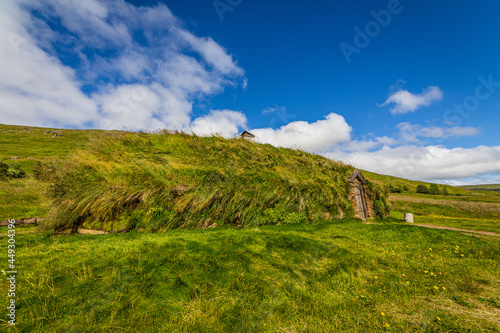 Turf houses in Iceland with grass roof under blue sky