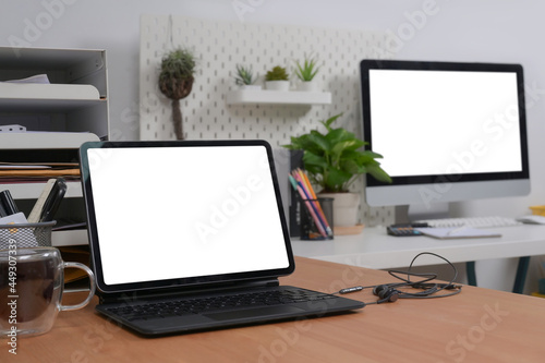 Mock up computer tablet with blank screen on wooden table in home office.