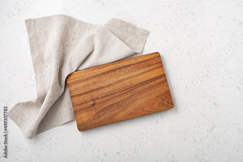 Wooden cutting board with linen napkin on marble table