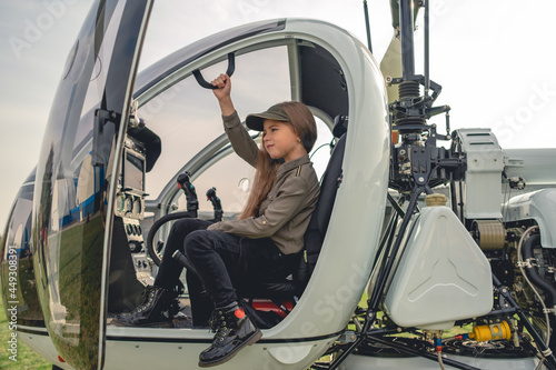 Tween girl sitting on pilot seat in modern helicopter cockpit