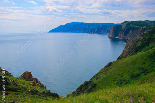 A beautiful summer landscape. A blue bay reflects a bright sky. A coastline of the Lake Baikal. Wonderful views of the Olkhon island. A green meadow on the shore.