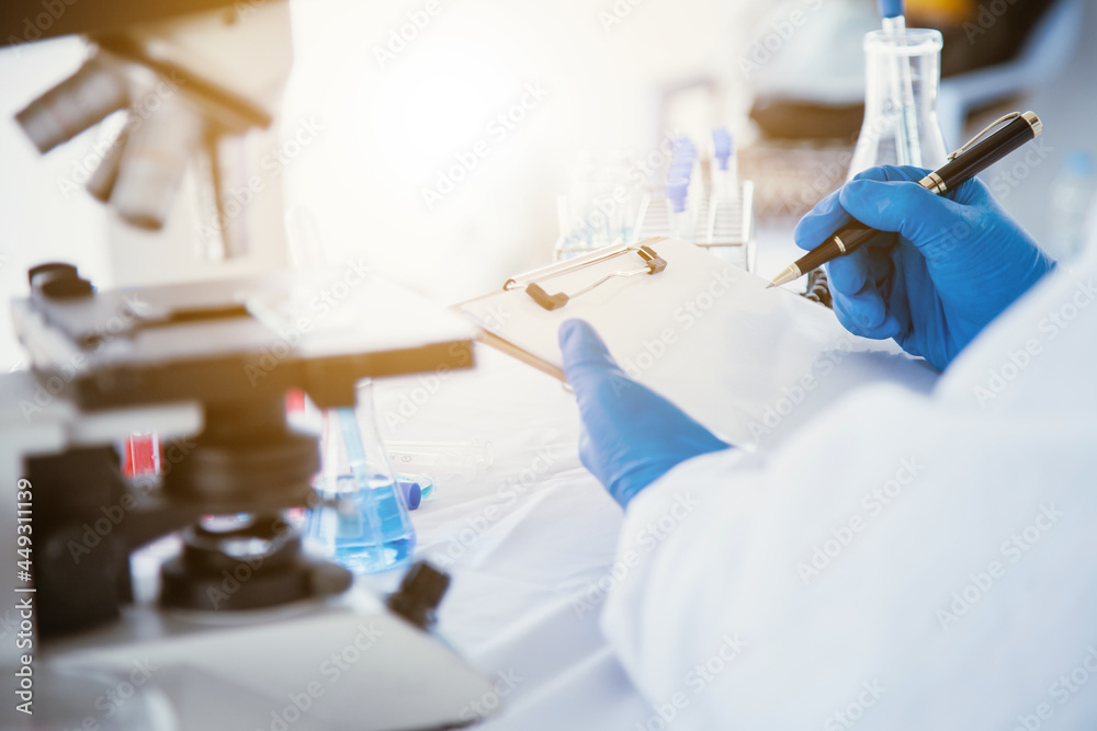 medical or scientific researcher researching and experimenting Multi-colored solution, vial and microscope In the laboratory or in the laboratory by wearing blue gloves and white clothing completely. medical or scientific researcher researching and experimenting Multi-colored solution, vial and microscope In the laboratory or in the laboratory by wearing blue gloves and white clothing completely.