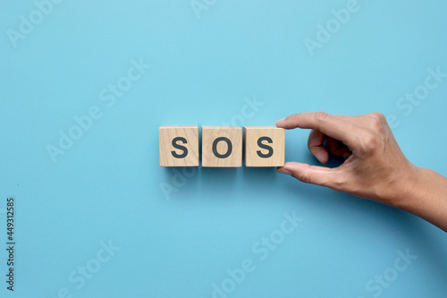 Wooden cubes with the word sos. A person asks for help
