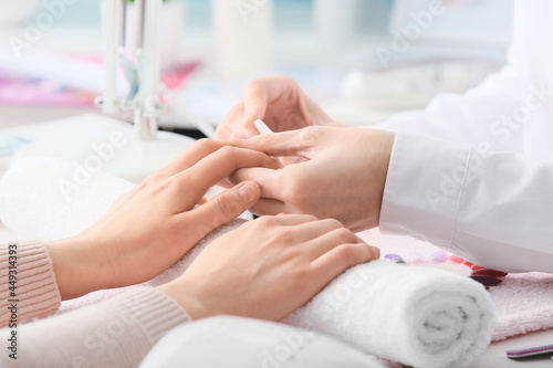 Manicure master working with female client in beauty salon, closeup