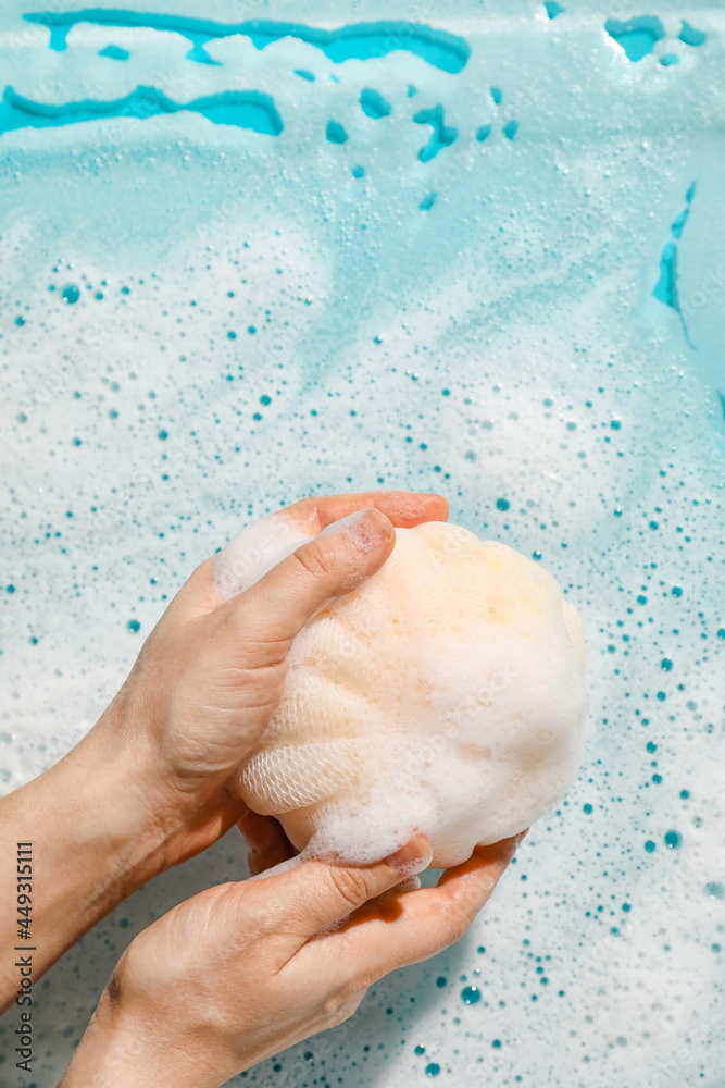 Woman holding loofah with foam on color background