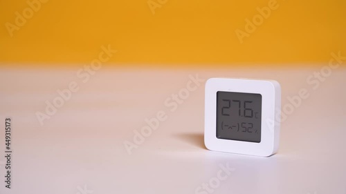 Compact home thermohygrometer on a yellow background controls changes of humidity and temperature. Device for smart home system. Temperature adjustment. The concept of a healthy lifestyle. Close-up vi photo