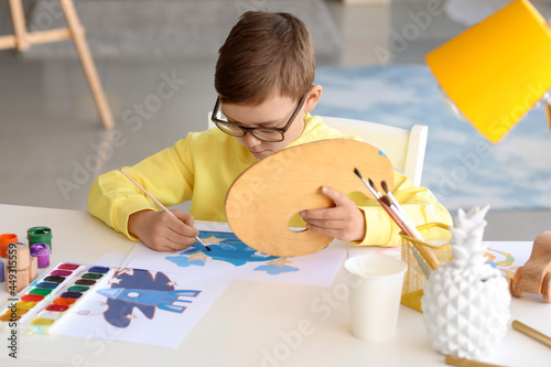 Cute little boy painting at...