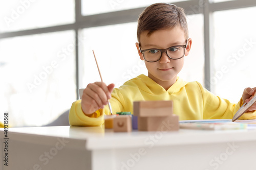 Cute little boy painting at...
