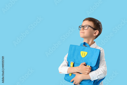Little schoolboy with backpack on color background photo