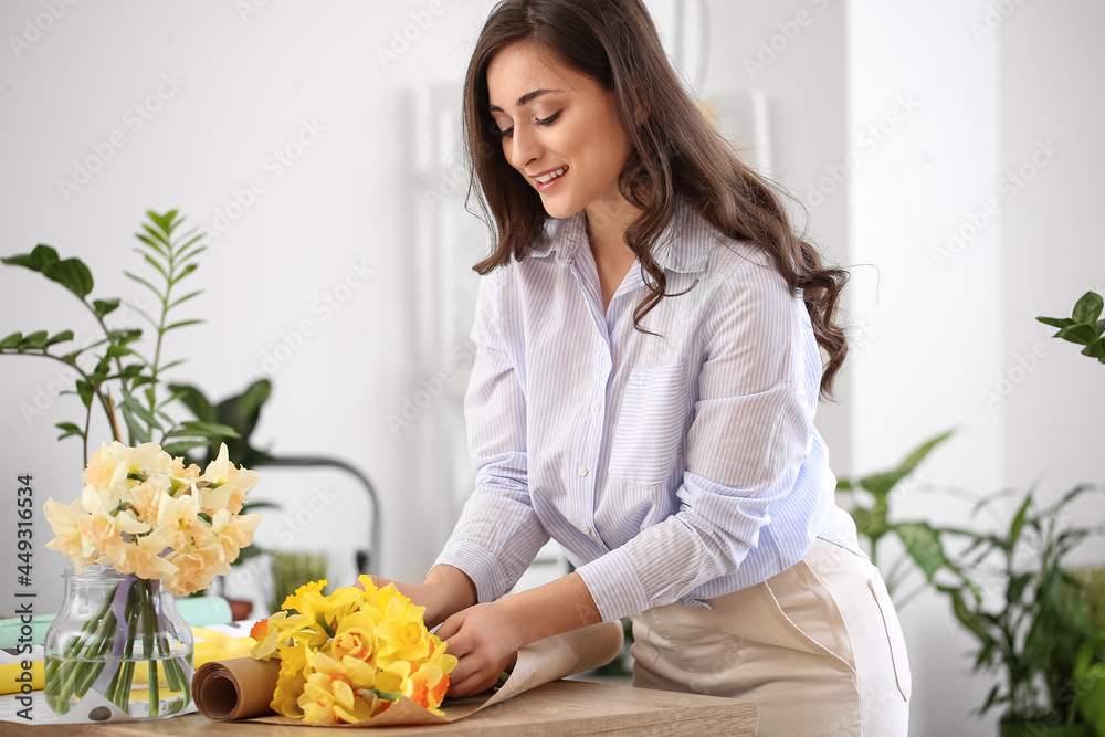 Female florist with beautiful narcissus flowers in workshop Female florist with beautiful narcissus flowers in workshop